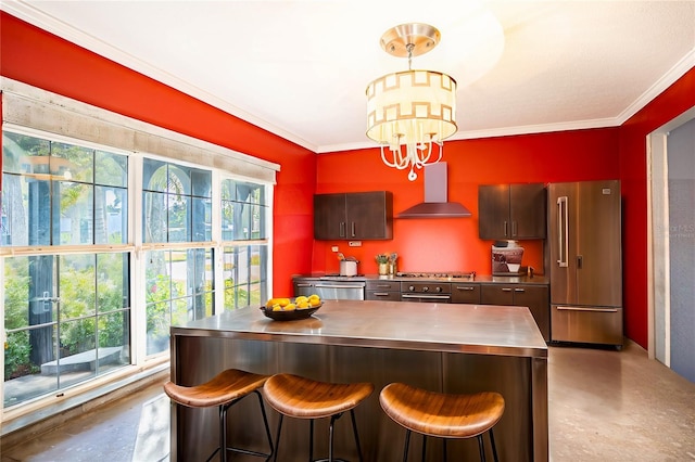 kitchen featuring pendant lighting, a breakfast bar, wall chimney exhaust hood, appliances with stainless steel finishes, and stainless steel counters