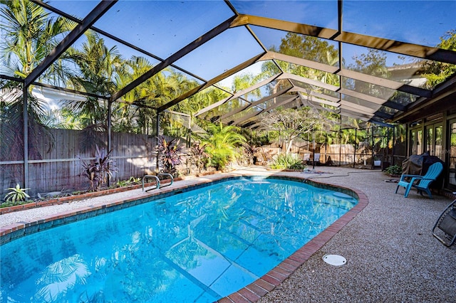 view of pool with glass enclosure and a patio