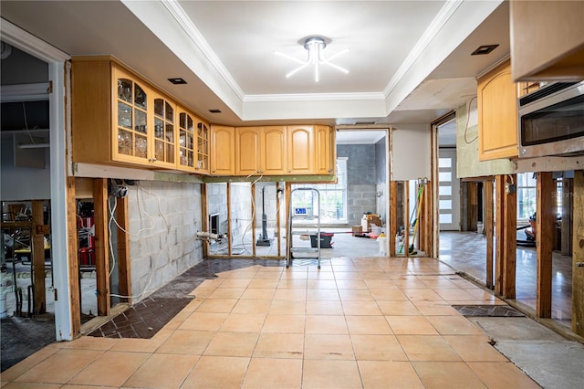 kitchen with light tile patterned floors, light brown cabinetry, and a tray ceiling