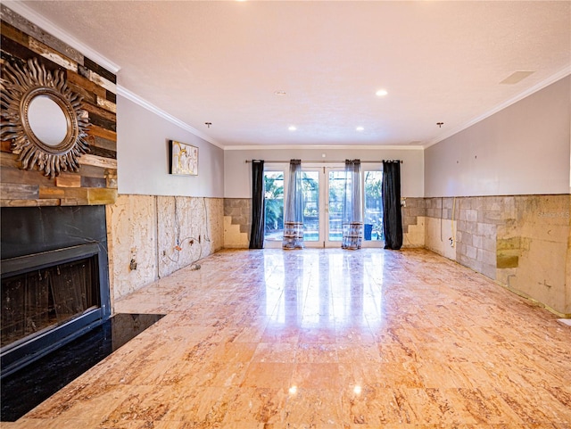 unfurnished living room with a large fireplace, ornamental molding, tile walls, and french doors