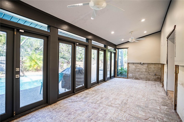 interior space featuring lofted ceiling, ceiling fan, crown molding, and tile walls