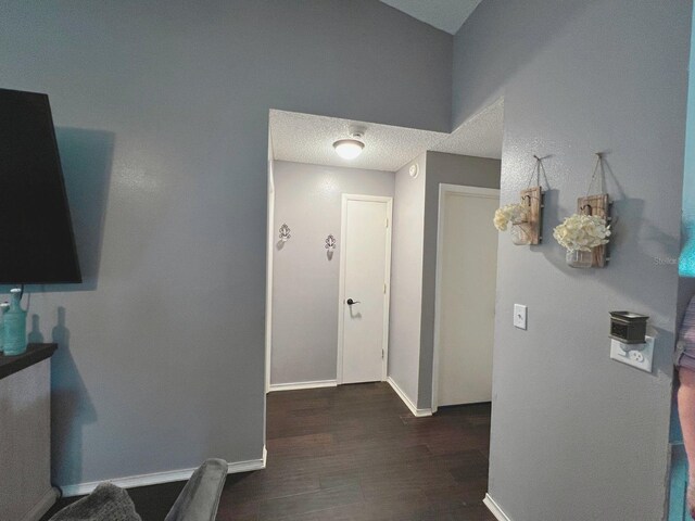 corridor with dark hardwood / wood-style flooring and a textured ceiling