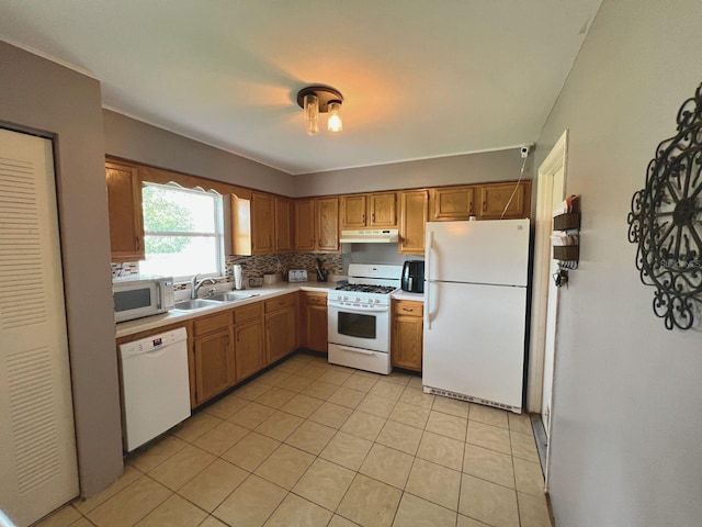 kitchen with decorative backsplash, light tile patterned floors, white appliances, and sink