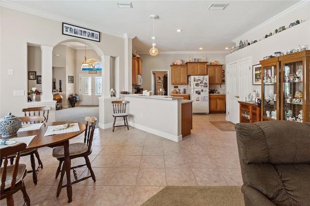 kitchen featuring light tile patterned flooring, decorative columns, white refrigerator, kitchen peninsula, and crown molding