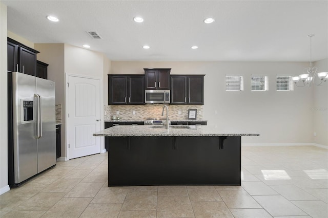 kitchen featuring light stone counters, sink, an island with sink, and stainless steel appliances