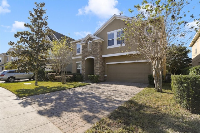 view of front of home with an attached garage, stone siding, decorative driveway, stucco siding, and a front lawn