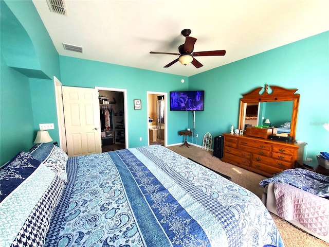 carpeted bedroom featuring connected bathroom, ceiling fan, a closet, and a walk in closet