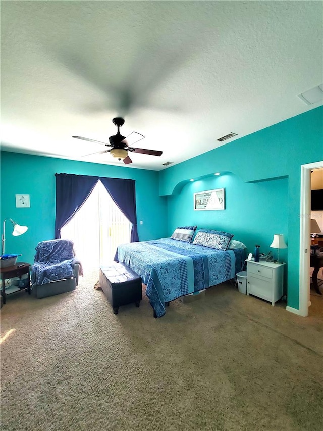 bedroom featuring ceiling fan, carpet floors, and a textured ceiling