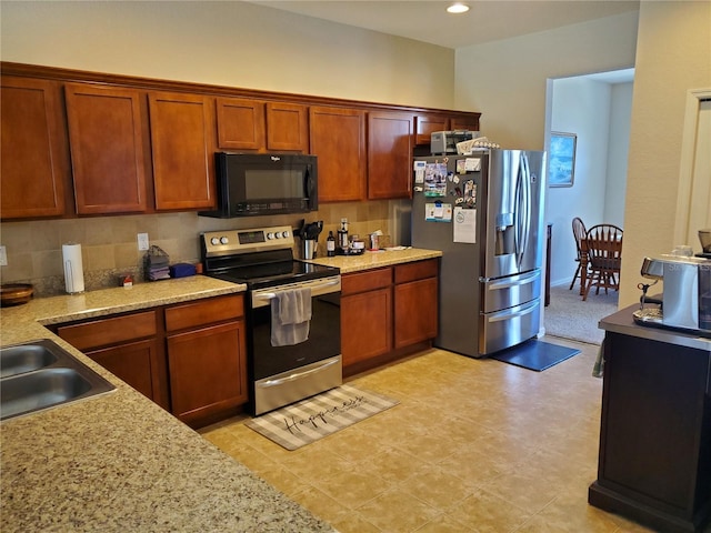 kitchen featuring tasteful backsplash, sink, light stone countertops, and appliances with stainless steel finishes