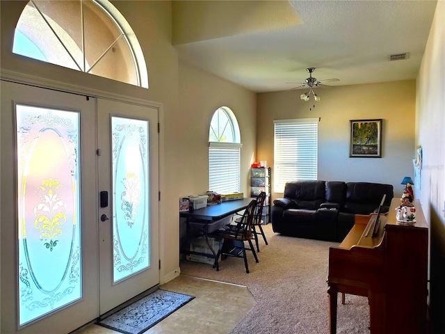 foyer with carpet floors, ceiling fan, and french doors