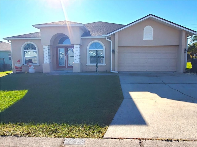 view of front of home with a garage, a front lawn, and french doors