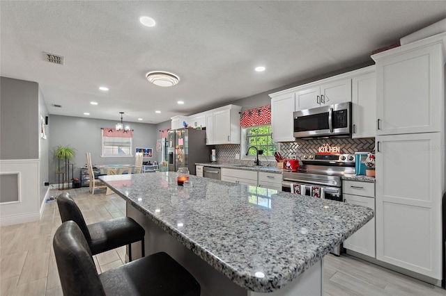 kitchen with pendant lighting, a center island, sink, and appliances with stainless steel finishes