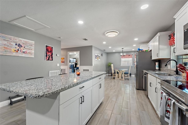 kitchen featuring white cabinets, a kitchen island, light wood-type flooring, and sink