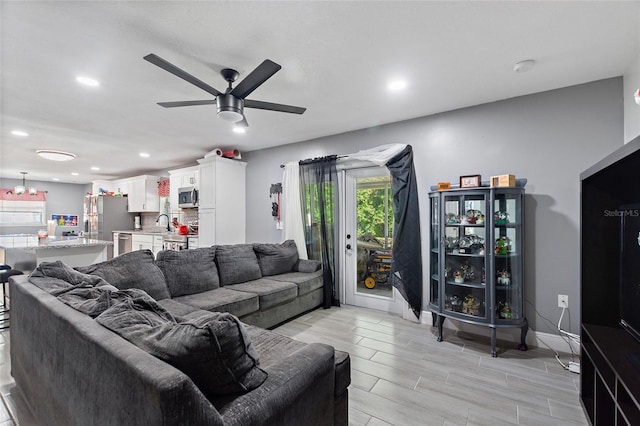 living room with ceiling fan, sink, and light hardwood / wood-style floors