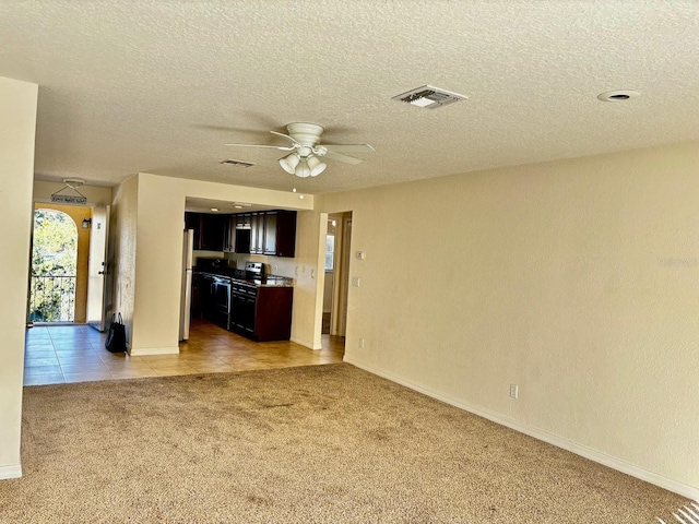 unfurnished living room with a textured ceiling, light colored carpet, and ceiling fan