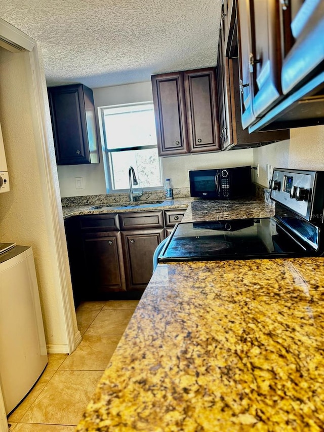 kitchen with light tile patterned flooring, dark brown cabinets, black appliances, and sink