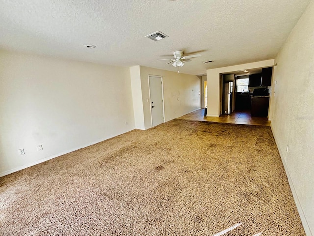 unfurnished room with a textured ceiling, carpet floors, and ceiling fan