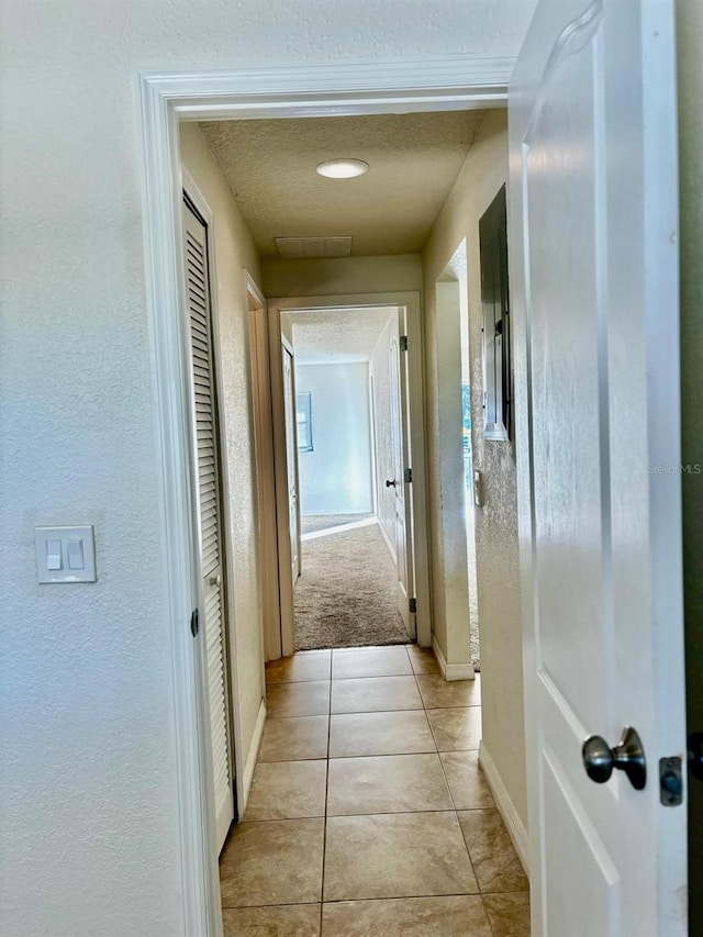 hall with light tile patterned floors and a textured ceiling