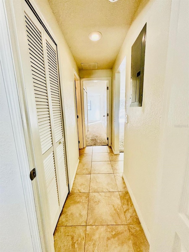 corridor featuring a textured ceiling and light tile patterned flooring