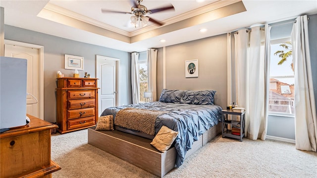 bedroom with ceiling fan, ornamental molding, a tray ceiling, and light carpet