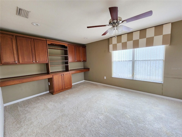 kitchen featuring ceiling fan, built in desk, and light carpet