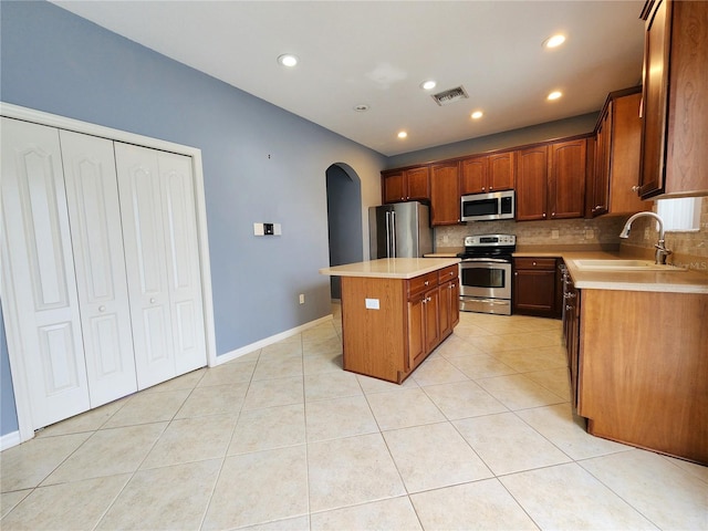 kitchen featuring sink, light tile patterned floors, stainless steel appliances, and a kitchen island