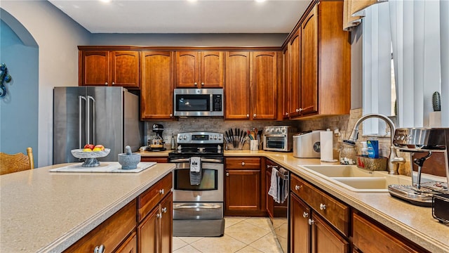 kitchen with light tile patterned flooring, stainless steel appliances, sink, and backsplash