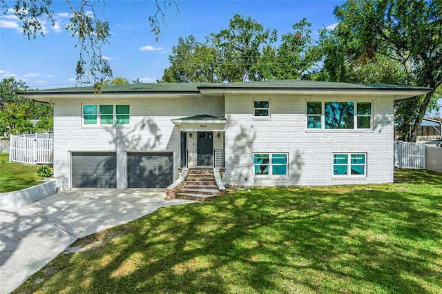 raised ranch featuring a front lawn and a garage