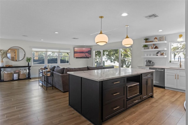 kitchen with hanging light fixtures, sink, stainless steel appliances, and a wealth of natural light