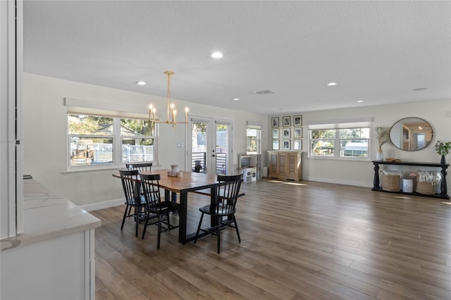 dining area featuring a chandelier, dark hardwood / wood-style flooring, a textured ceiling, and french doors