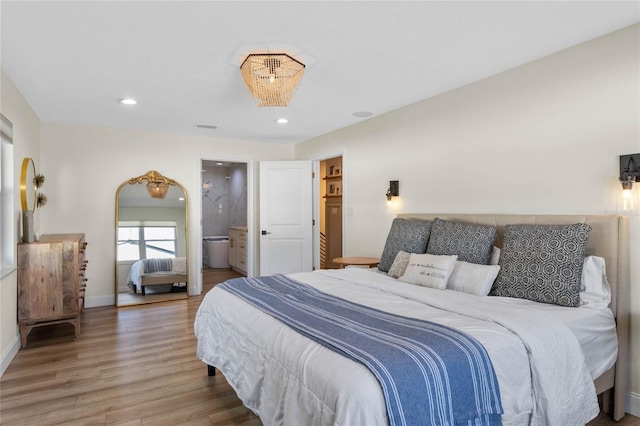 bedroom with ensuite bath and wood-type flooring