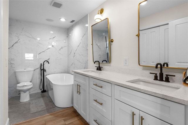 bathroom featuring a bathtub, vanity, wood-type flooring, tile walls, and toilet