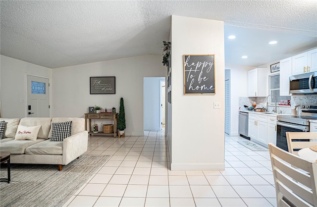 tiled living room featuring a textured ceiling, sink, and vaulted ceiling