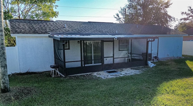 rear view of property featuring a lawn and a sunroom