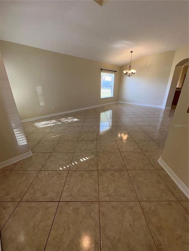 empty room featuring tile patterned flooring, a notable chandelier, and lofted ceiling