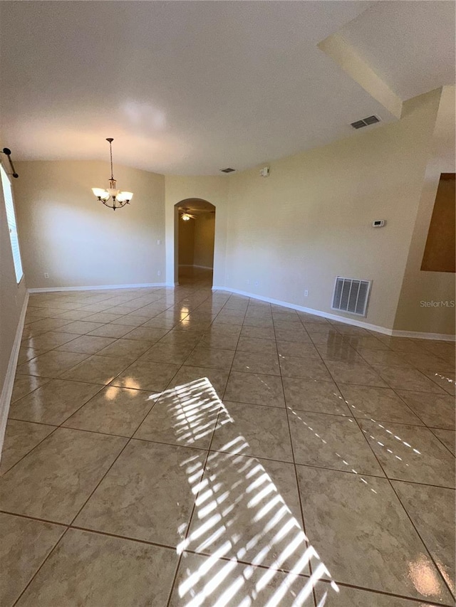 empty room featuring tile patterned flooring, a textured ceiling, and a notable chandelier