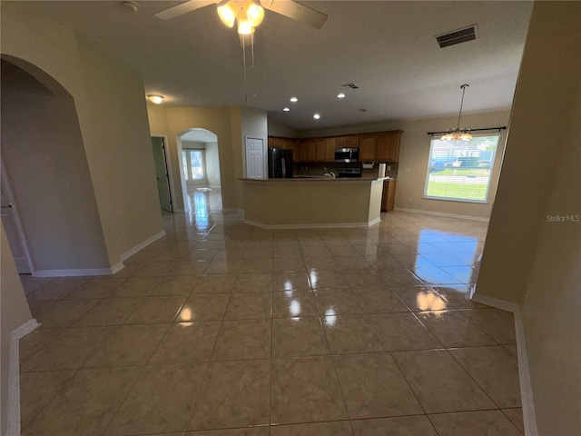 kitchen with ceiling fan, black fridge, kitchen peninsula, decorative light fixtures, and light tile patterned floors