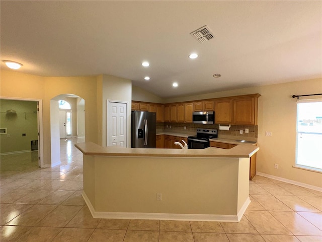 kitchen featuring appliances with stainless steel finishes, backsplash, sink, light tile patterned floors, and lofted ceiling