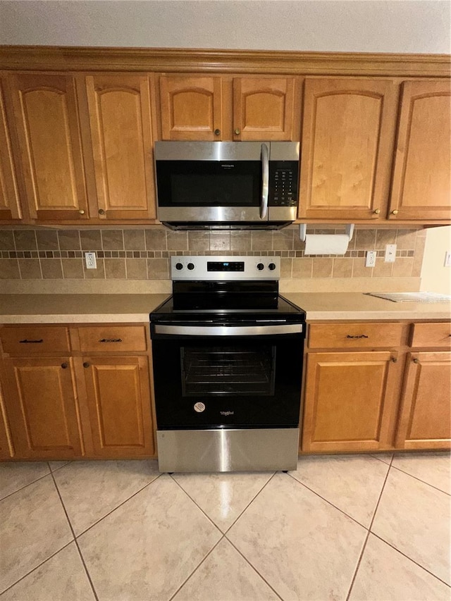 kitchen with decorative backsplash, light tile patterned floors, and stainless steel appliances