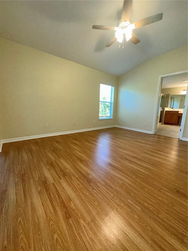 spare room with ceiling fan, vaulted ceiling, and light wood-type flooring