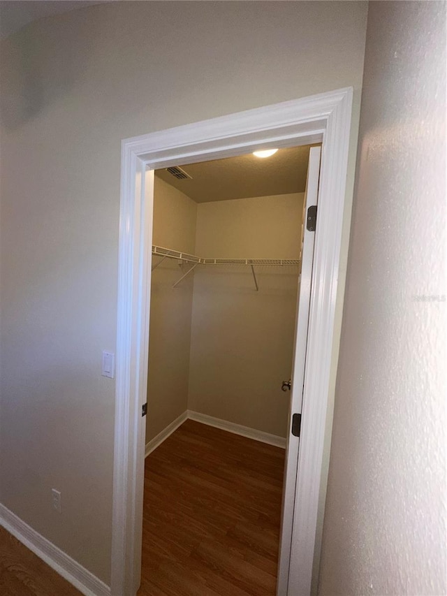 walk in closet with dark hardwood / wood-style flooring