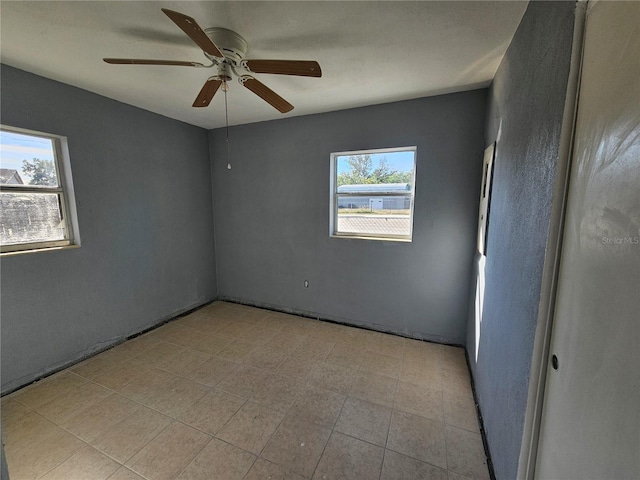 empty room with ceiling fan and a wealth of natural light