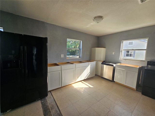 kitchen with washer / clothes dryer, white cabinets, black appliances, and a textured ceiling