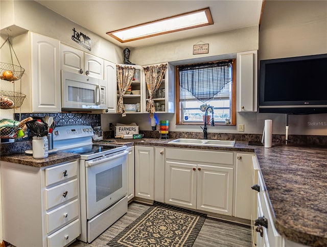 kitchen with white appliances, backsplash, sink, hardwood / wood-style flooring, and white cabinetry