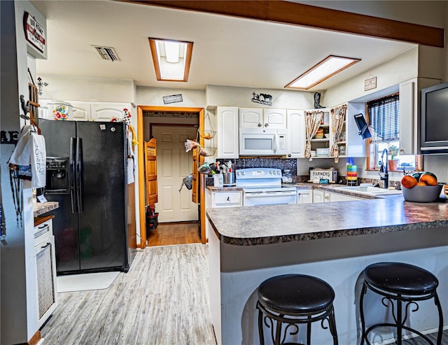 kitchen featuring white cabinetry, sink, white appliances, and kitchen peninsula