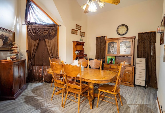 dining area with ceiling fan, wood-type flooring, and vaulted ceiling