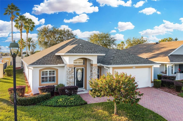 ranch-style house featuring a garage, roof with shingles, decorative driveway, a front lawn, and stucco siding