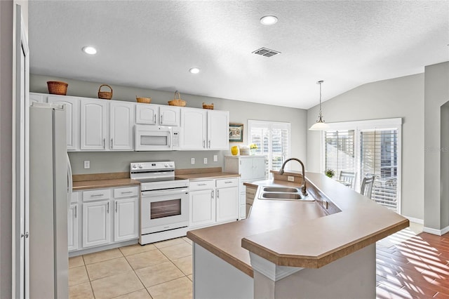 kitchen featuring visible vents, white cabinetry, vaulted ceiling, a sink, and white appliances