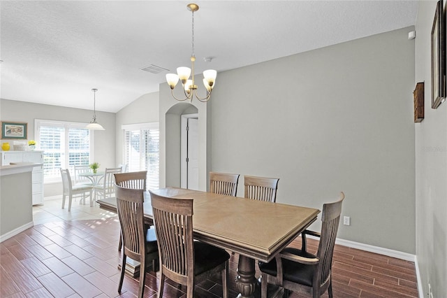 dining area featuring visible vents, baseboards, lofted ceiling, wood tiled floor, and a chandelier