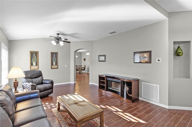 living room with wood tiled floor, a fireplace, visible vents, and arched walkways